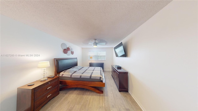 bedroom featuring ceiling fan, light hardwood / wood-style floors, and a textured ceiling