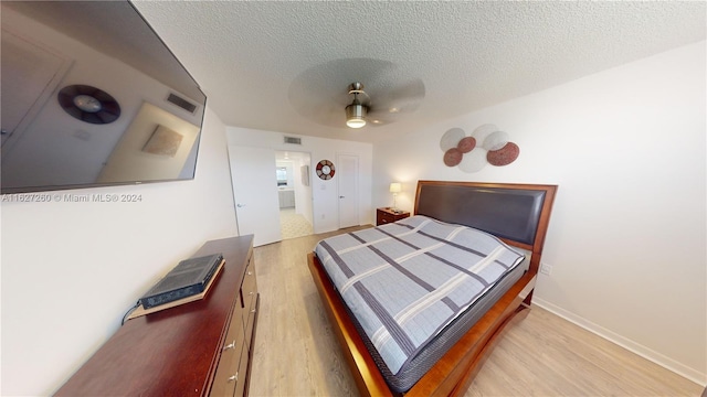 bedroom featuring ceiling fan, light hardwood / wood-style floors, and a textured ceiling