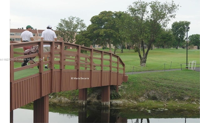 surrounding community with a water view and a lawn