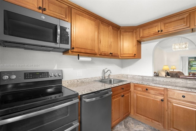 kitchen with stainless steel appliances, sink, and light stone counters