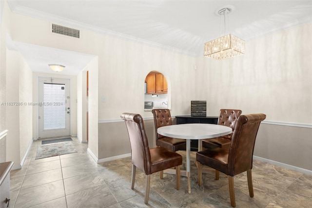 dining room featuring tile patterned floors, crown molding, and an inviting chandelier