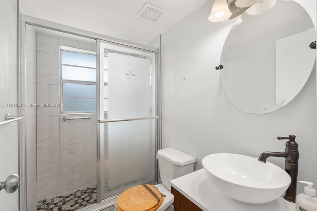 bathroom with walk in shower, vanity, and toilet