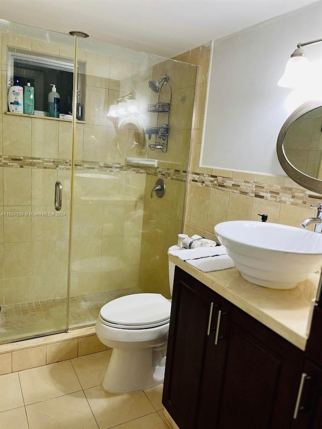 bathroom with vanity, tile patterned floors, tile walls, an enclosed shower, and toilet