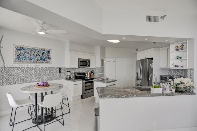 kitchen featuring a peninsula, a sink, visible vents, white cabinetry, and appliances with stainless steel finishes