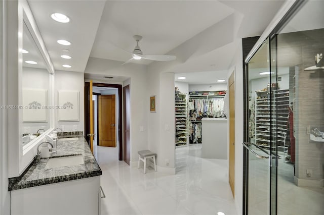 bathroom with double vanity, a spacious closet, a sink, and a shower stall