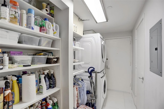 washroom featuring laundry area, electric panel, stacked washer / dryer, and light tile patterned flooring