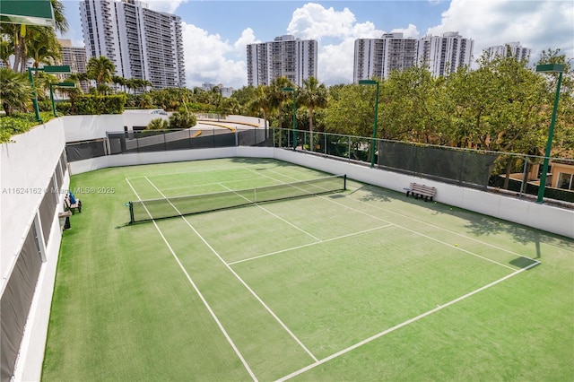 view of tennis court with a view of city and fence