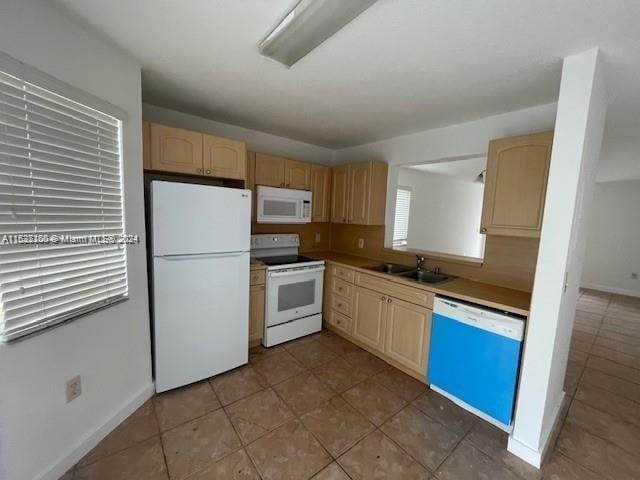 kitchen with light brown cabinetry, tile patterned flooring, sink, and white appliances