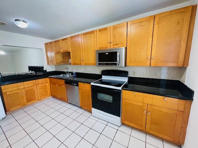 kitchen featuring sink, appliances with stainless steel finishes, backsplash, and light tile patterned flooring