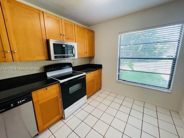 kitchen with decorative backsplash, appliances with stainless steel finishes, and light tile patterned flooring