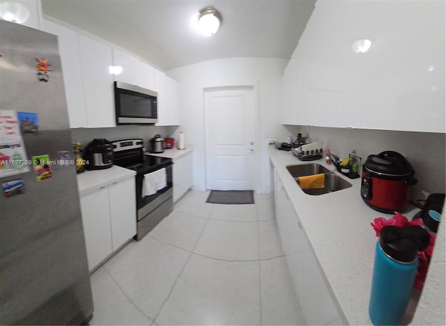 kitchen featuring appliances with stainless steel finishes, light tile patterned flooring, white cabinets, and sink