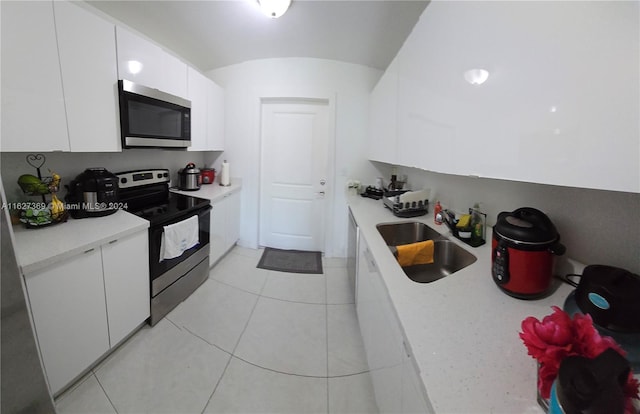 kitchen with white cabinetry, stainless steel appliances, light tile patterned floors, and sink