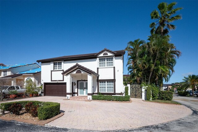 7949 NW 188th Ter, Hialeah, FL 33015 - view of front of property with an attached garage, curved driveway, a tile roof, stucco siding, and french doors