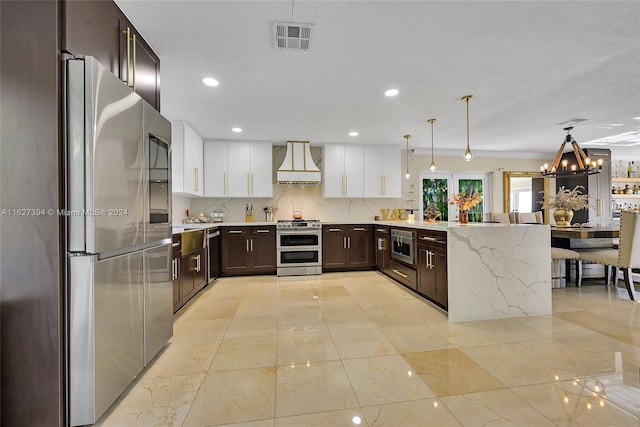7949 NW 188th Ter, Hialeah, FL 33015 - kitchen with premium range hood, appliances with stainless steel finishes, dark brown cabinets, a peninsula, and a chandelier