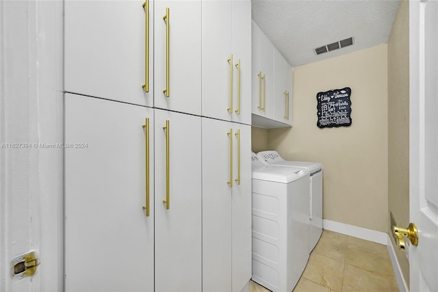 clothes washing area with cabinets, light tile patterned floors, a textured ceiling, and independent washer and dryer