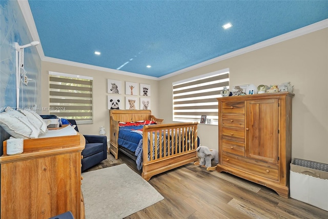 bedroom featuring a textured ceiling, ornamental molding, and wood-type flooring