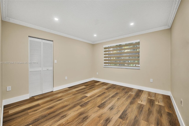 empty room featuring a textured ceiling, hardwood / wood-style floors, and ornamental molding