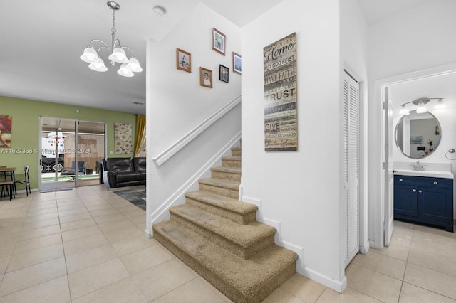 stairway with sink, a chandelier, and light tile patterned floors