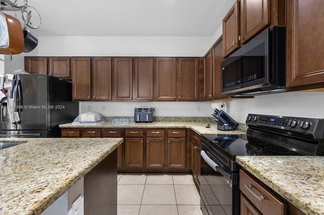 kitchen with black appliances, light tile patterned floors, and light stone counters