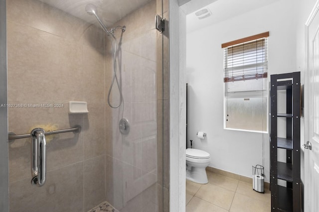 bathroom featuring toilet, a tile shower, and tile patterned flooring