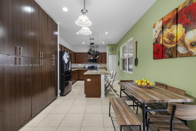 kitchen featuring hanging light fixtures, a center island, dark brown cabinetry, appliances with stainless steel finishes, and light tile patterned floors