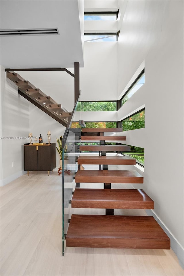 staircase with wood-type flooring and a towering ceiling