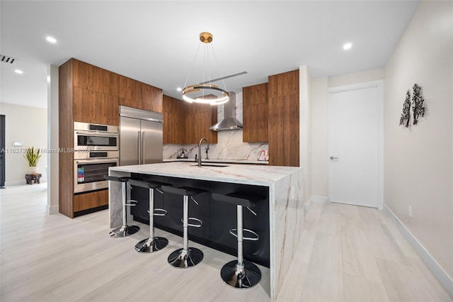 kitchen with a kitchen breakfast bar, sink, an island with sink, appliances with stainless steel finishes, and decorative light fixtures