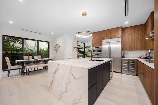 kitchen with pendant lighting, a kitchen island with sink, appliances with stainless steel finishes, tasteful backsplash, and a chandelier