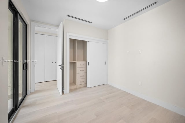 unfurnished bedroom featuring light hardwood / wood-style flooring and a closet