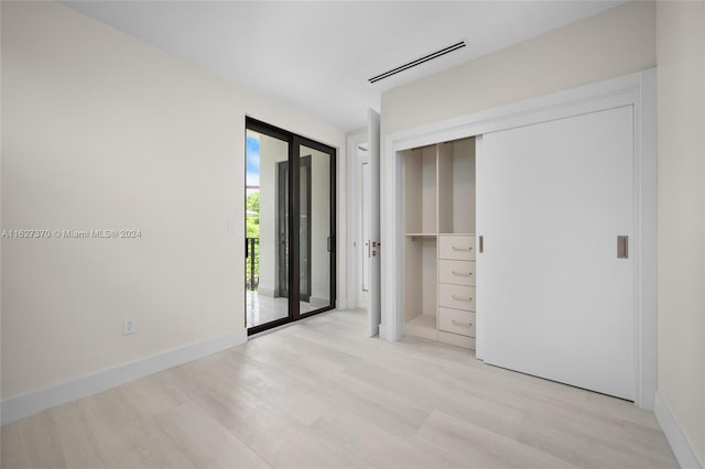 unfurnished bedroom with access to outside, a closet, and light wood-type flooring