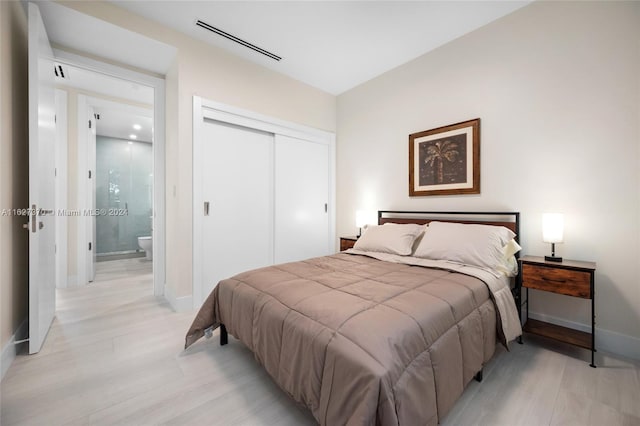 bedroom featuring light hardwood / wood-style floors, ensuite bath, and a closet