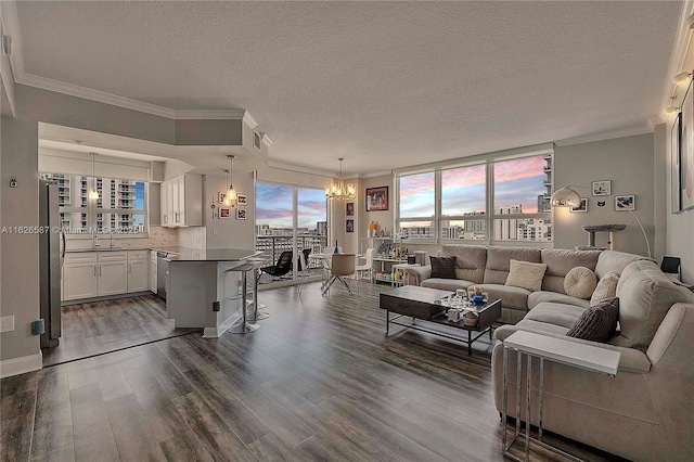 living room with a textured ceiling, ornamental molding, dark wood finished floors, and a notable chandelier