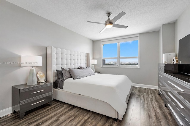 bedroom with ceiling fan, a textured ceiling, baseboards, and dark wood-type flooring