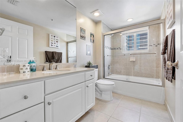 bathroom featuring visible vents, toilet, tile patterned floors, combined bath / shower with glass door, and vanity