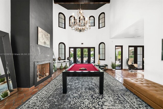 game room with french doors, a towering ceiling, a notable chandelier, and billiards