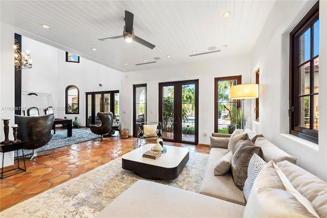 living room featuring a high ceiling, french doors, ceiling fan with notable chandelier, light tile patterned floors, and wood ceiling