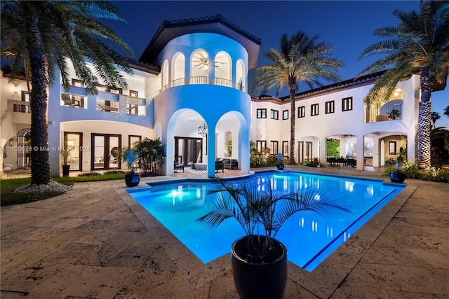 pool at twilight with a patio area and french doors