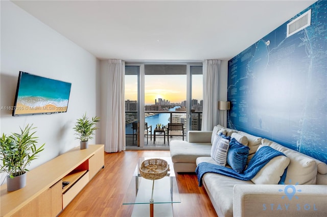 living room featuring a water view, hardwood / wood-style floors, and a wall of windows