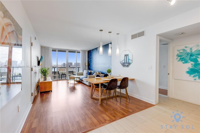 dining room with hardwood / wood-style flooring and a wall of windows