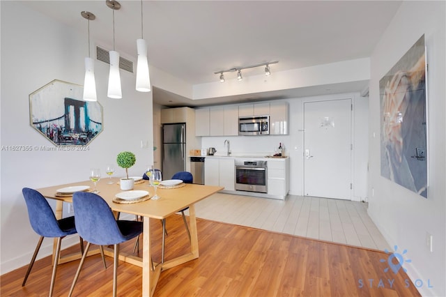 dining area with light tile patterned flooring, sink, and rail lighting