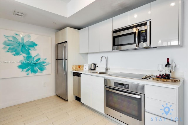 kitchen with white cabinetry, stainless steel appliances, and sink