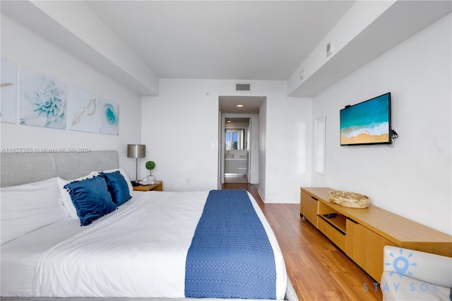 bedroom featuring hardwood / wood-style flooring and ensuite bath