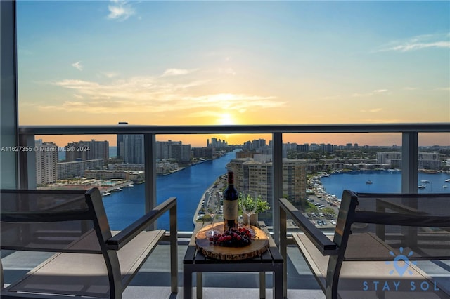 balcony at dusk featuring a water view