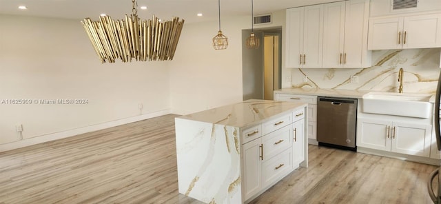 kitchen with stainless steel dishwasher, light hardwood / wood-style floors, light stone countertops, decorative backsplash, and decorative light fixtures