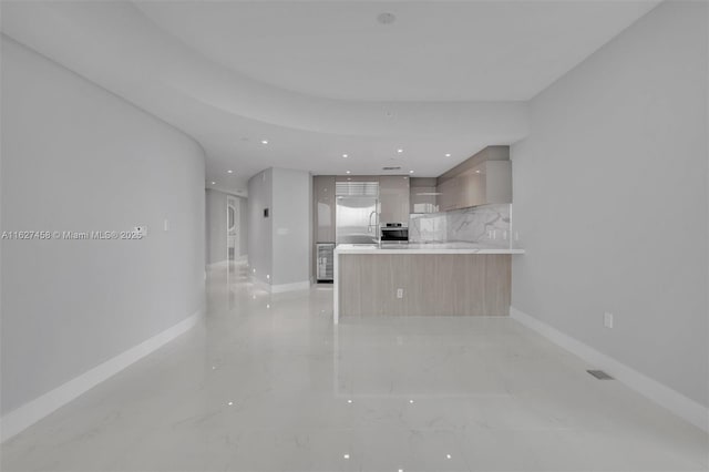 kitchen with backsplash, appliances with stainless steel finishes, kitchen peninsula, and light brown cabinets