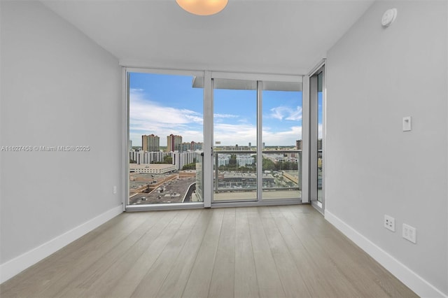 unfurnished room featuring expansive windows and light wood-type flooring