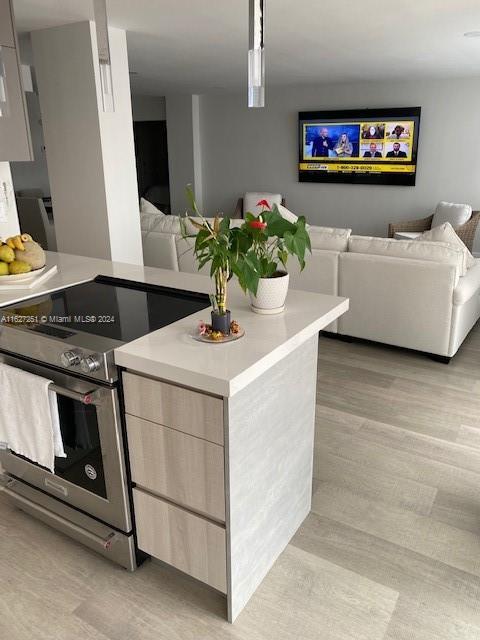 kitchen with a center island, hanging light fixtures, stainless steel electric range, and light hardwood / wood-style flooring