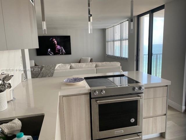 kitchen with light brown cabinets, floor to ceiling windows, and high end stainless steel range oven