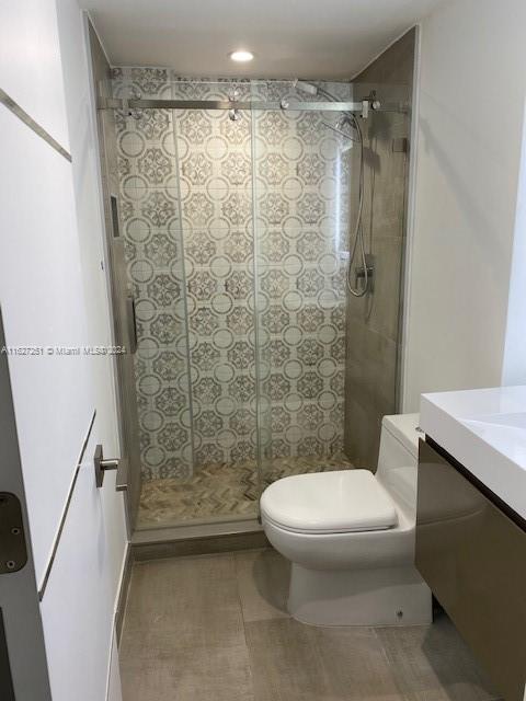 bathroom with tile patterned floors, toilet, vanity, and a tile shower