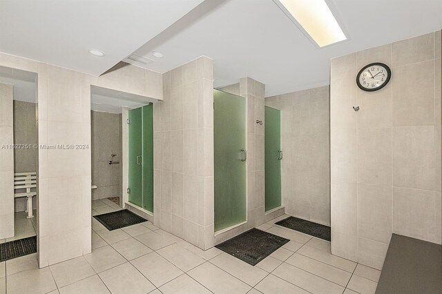 bathroom with a tile shower, tile patterned flooring, and tile walls